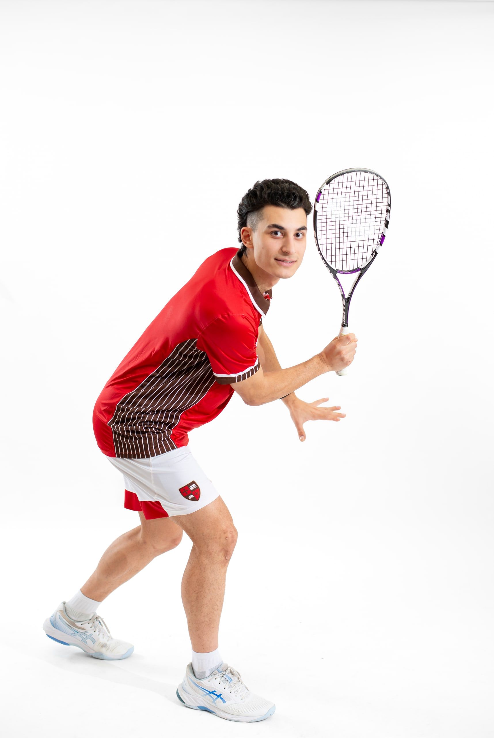 Emirhan Sen in a red St. Lawrence kit in a ready stance, racket up